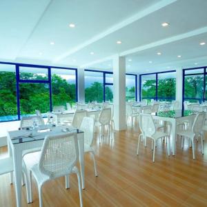 a restaurant with white tables and chairs and windows at Ruhe Suites Coron in Coron