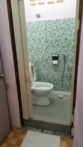a bathroom with a toilet and a green tiled shower at JSW Inn in Gelugor