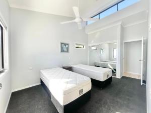 a white bedroom with two beds and a ceiling fan at Sunsets on Moreton 5 Ramosus in Tangalooma