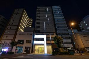 dos edificios altos en una ciudad por la noche en Nico Hotel en Osaka