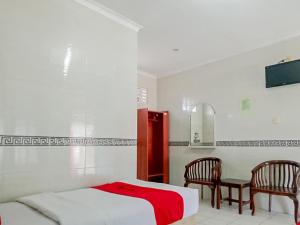 a white bedroom with a bed and two chairs at RedDoorz Syariah @ Hotel Sidomulyo Pacitan in Pacitan