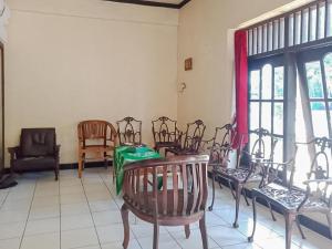 une chambre avec des chaises, une table et des fenêtres dans l'établissement RedDoorz Syariah @ Hotel Sidomulyo Pacitan, à Pacitan
