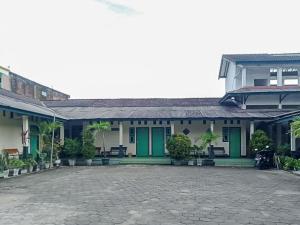 un bâtiment avec des portes vertes et une cour dans l'établissement RedDoorz Syariah @ Hotel Sidomulyo Pacitan, à Pacitan