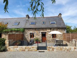 a stone house with a table and an umbrella at Gites de lardanva in Lardanva