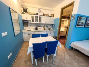 une cuisine avec une table blanche et des chaises bleues dans l'établissement Apartma IVY, à Ankaran