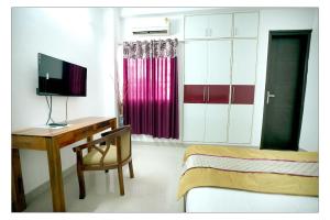 um quarto com uma secretária, uma cama e uma televisão em Gupta Residency em Noida