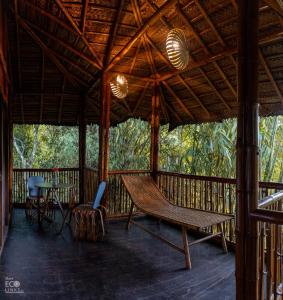 eine Veranda mit einer Hängematte sowie einem Tisch und Stühlen in der Unterkunft Uravu Bamboo Grove Resort in Wayanad