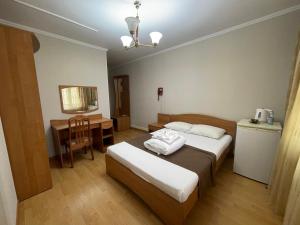 1 dormitorio con 2 camas, mesa y escritorio en Victoria Palace en Atyraū