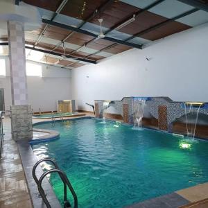 uma piscina com uma fonte de água num edifício em Cloudy Cloud Farm Resort em Izkī