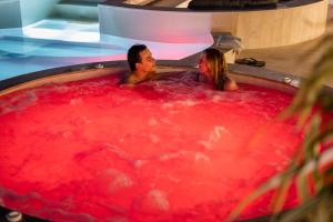 un hombre y una mujer en un jacuzzi lleno de líquido rojo en Avaton Luxury Resort and Spa Access the Enigma - Adults Only & Kids 14 Plus- en Asprovalta