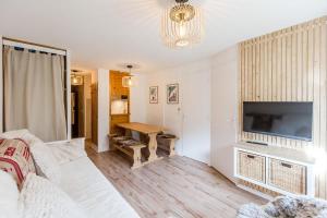 een woonkamer met een bank, een televisie en een tafel bij Appartement Les Arcs Ski aux pieds à Vallandry in Landry