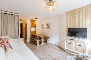 a living room with a couch and a television and a table at Appartement Les Arcs Ski aux pieds à Vallandry in Landry