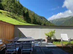 eine Terrasse mit einem Tisch, Stühlen und einem Hügel in der Unterkunft 3-Zimmer Appartement in Zwieselstein (Sölden) in Sölden