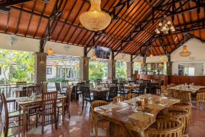 un restaurante con mesas y sillas de madera y un bar en Jimbarwana Hotel en Negara