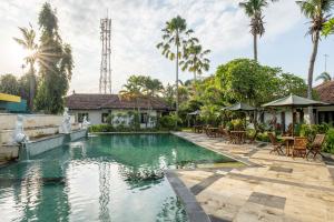 a swimming pool with tables and chairs in front of a house at Jimbarwana Hotel in Negara