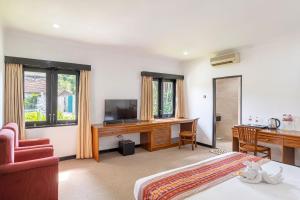 a hotel room with a bed and a desk with a computer at Jimbarwana Hotel in Negara