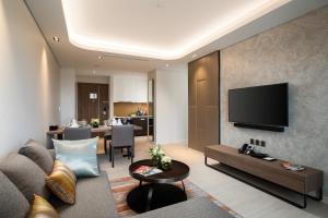 a living room with a couch and a television on a wall at Oakwood Residence Hanoi in Hanoi