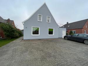 a white house with a car parked in a driveway at Bakker Huus EG in Emden
