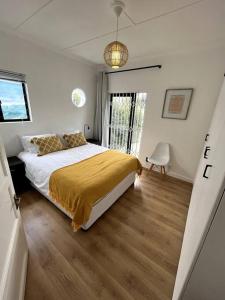 ein Schlafzimmer mit einem Bett mit einer gelben Decke darauf in der Unterkunft Centrally located modern 2-bedroom home & parking in Kapstadt