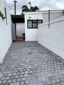 a white house with a brick driveway and a fence at Centrally located modern 2-bedroom home & parking in Cape Town