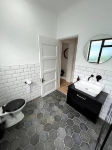 a bathroom with a sink and a toilet and a mirror at Centrally located modern 2-bedroom home & parking in Cape Town