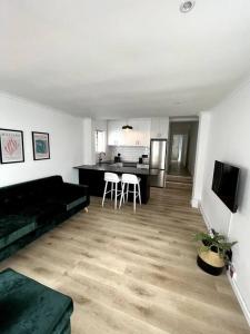 sala de estar con sofá negro y cocina en Centrally located modern 2-bedroom home & parking, en Ciudad del Cabo