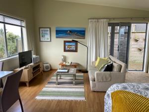 a living room with a couch and a tv at Chalet Cullen, in Mangawhai