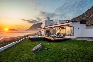 une maison avec vue sur l'océan au coucher du soleil dans l'établissement OnTheRocksBB Solar Powered Guesthouse and Ocean Lodge, à Bettyʼs Bay