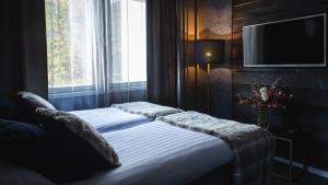 1 Schlafzimmer mit 2 Betten und einem TV an der Wand in der Unterkunft Hotel Golden Circle Suites in Rovaniemi
