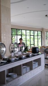 a man in a kitchen with plates and mirrors at The Green Peak, ARTOTEL Curated in Cisarua