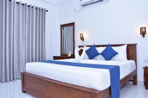 a bedroom with a large bed with blue and white sheets at Ceylon Relax Villa in Moragalla