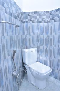 La salle de bains est pourvue de toilettes blanches et de carrelage bleu. dans l'établissement Ceylon Relax Villa, à Moragalla