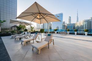 un groupe de chaises et un parasol sur un toit dans l'établissement Kasco Homes Waves Tower Business Bay, à Dubaï