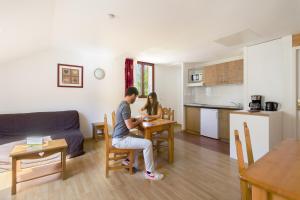 Ein Mann und eine Frau sitzen an einem Tisch im Wohnzimmer in der Unterkunft Garden & City Evian - Lugrin in Lugrin