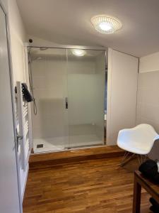 Una ducha de cristal en una habitación con una silla blanca en La Pierre Percée en Vertou
