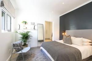 a bedroom with a bed and a chair and a mirror at Number 5104 - Contemporary Clifton Apartment in Cape Town