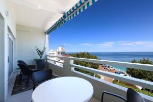 einen Balkon mit einem weißen Tisch, Stühlen und Meerblick in der Unterkunft Number 5104 - Contemporary Clifton Apartment in Kapstadt