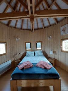 Schlafzimmer mit einem Bett mit blauer Bettwäsche und Fenstern in der Unterkunft Roulottes au pied du Vercors in Saint-Jean-en-Royans