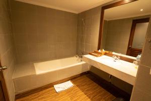 a bathroom with a tub and a sink and a mirror at New Sunari Lovina Beach Resort in Lovina