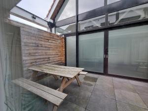 BB GUESTHOUSE في Wezembeek-Oppem: مقعد خشبي جالس في غرفة بها نوافذ