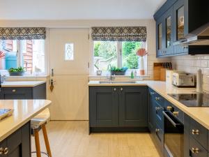 uma cozinha com armários azuis e um lavatório em Fairview Cottage em Moreton-in-Marsh
