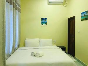 a bedroom with a white bed with towels on it at LETS GO HURAA in Huraa