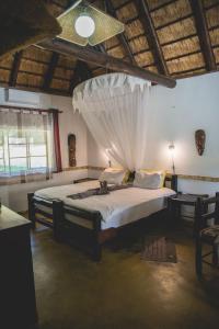 a bedroom with a bed with a mosquito net at Thokozani Lodge in White River