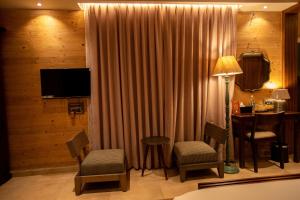 um quarto de hotel com uma mesa e cadeiras e uma televisão em AATHAVAN MATICHI ECO RESORT em Panhāla