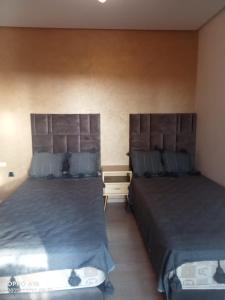 two beds sitting next to each other in a room at Appartement Prestigia Golf Marrakech in Marrakesh