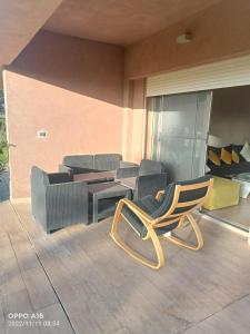 einen Stuhl sowie einen Tisch und Stühle auf einer Terrasse in der Unterkunft Appartement Prestigia Golf Marrakech in Marrakesch