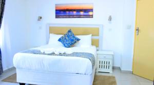 een slaapkamer met een groot wit bed met blauwe kussens bij Royal relax guest house in Palatswe