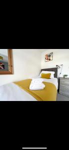 a bedroom with a bed with white sheets and yellow pillows at Homely and Deceptively large city house in Swansea