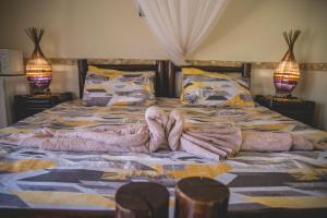 Una cama con una manta y dos lámparas. en Thokozani Lodge en White River