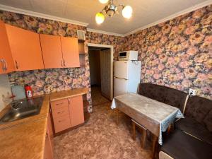 a kitchen with a refrigerator and a table in it at Стандарт Камзина 74 г. Павлодар in Pavlodar